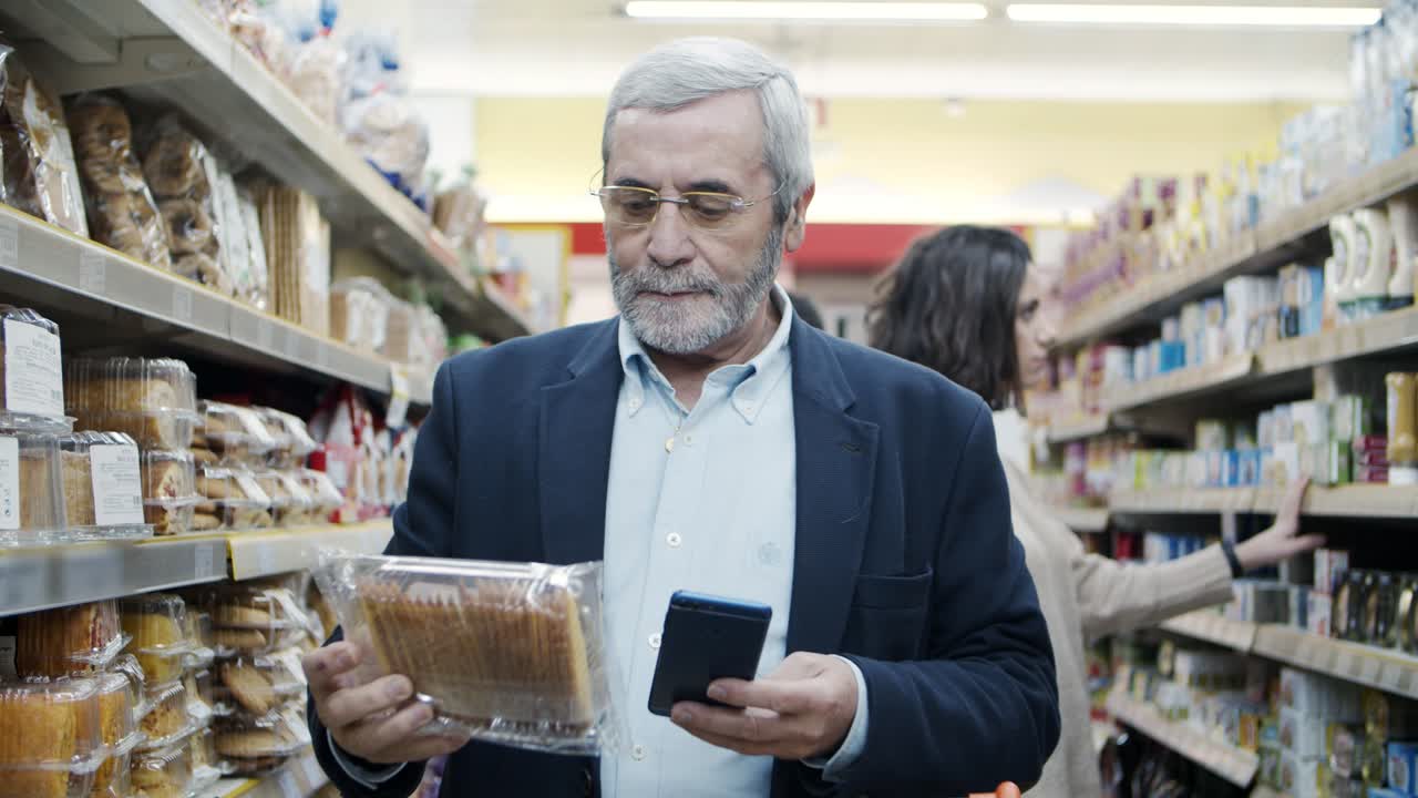 Uomo maturo che usa lo smartphone al supermercato
