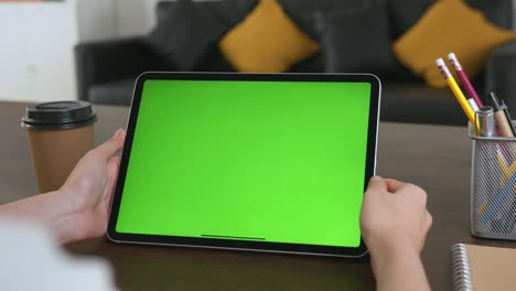 mujer sosteniendo una tableta digital con pantalla verde y dispositivo táctil navegando por internet.
