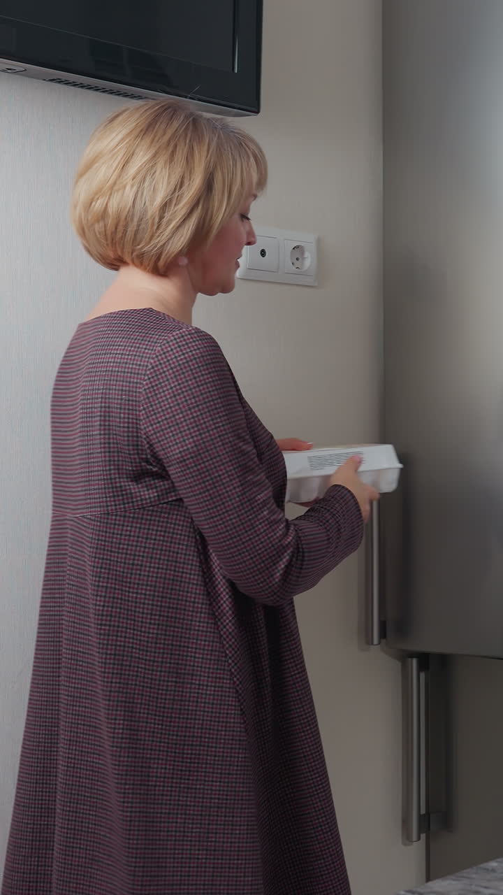 mujer abre el refrigerador para recuperar la caja de huevos y la coloca en la encimera en la cocina moderna, la escena captura la rutina diaria, la preparación de alimentos y el espacio de cocina bien organizado con iluminación cálida