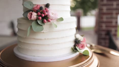 small, round, layered wedding cake on a table decorated with white frosting and pink flowers 1080p 60fps