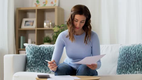 grey haired senior woman working with papers and calculating payment.elderly woman with grey hair working on paperwork and calculating bills