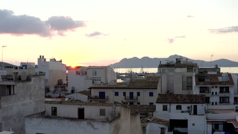 AERIAL:-Small-City-with-Port-on-Tropical-Island-with-Boats-and-Ocean-at-Small-Town-at-Sunrise-with-Mountains-in-Background-Vacation,-Travel,-Sunset