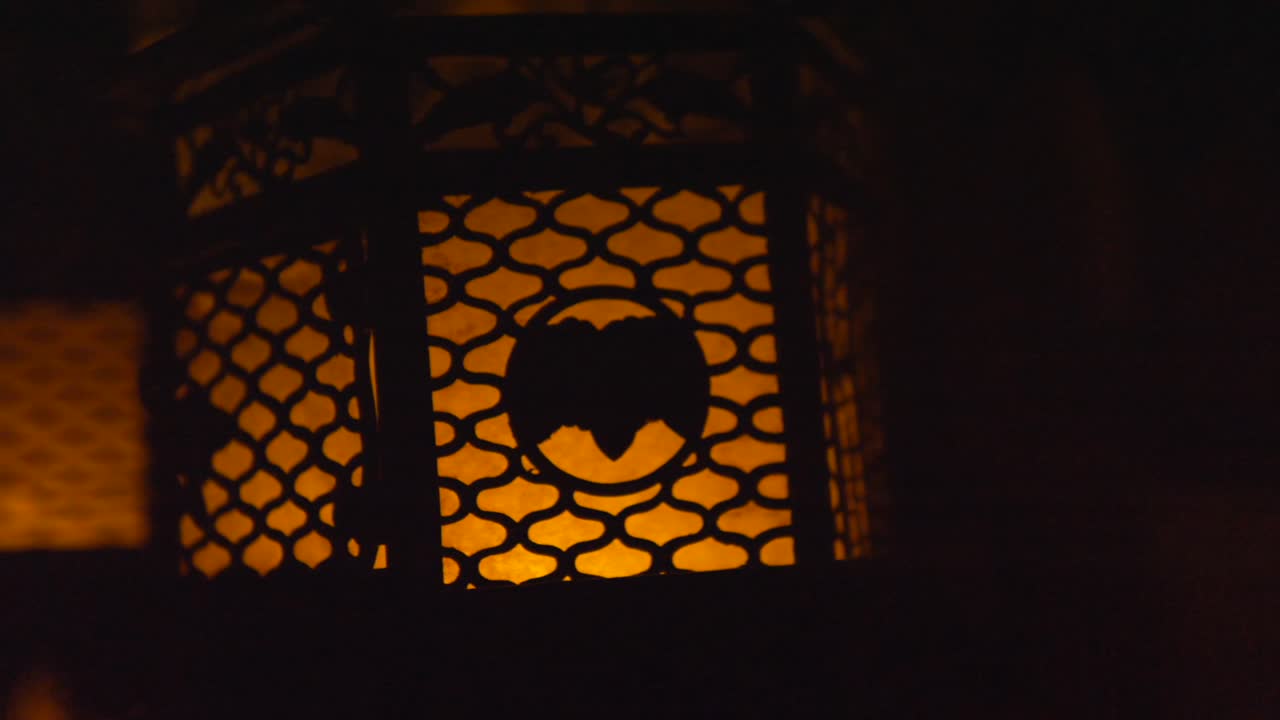 Dettaglio ravvicinato di lanterne tradizionali giapponesi illuminate da candele presso il Santuario Kasuga Taisha a Nara, Giappone. Le antiche lampade presentano intricate incisioni di kanji e cervi, proiettando un caldo bagliore.