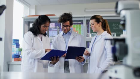 International-Group-of-Scientists-in-Laboratory.science-research,-work-and-people-concept-international-group-of-happy-scientists-with-clipboards-discussing-report-in-laboratory