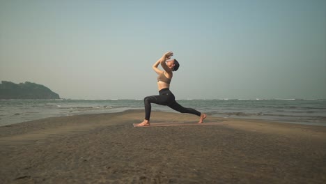 warrior one yoga pose at sunset on beach