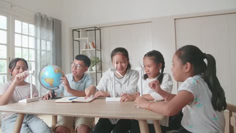 asian group of thoughtful kids study about ecology problems and their solution with wind turbine model and globe at school. renewable energy