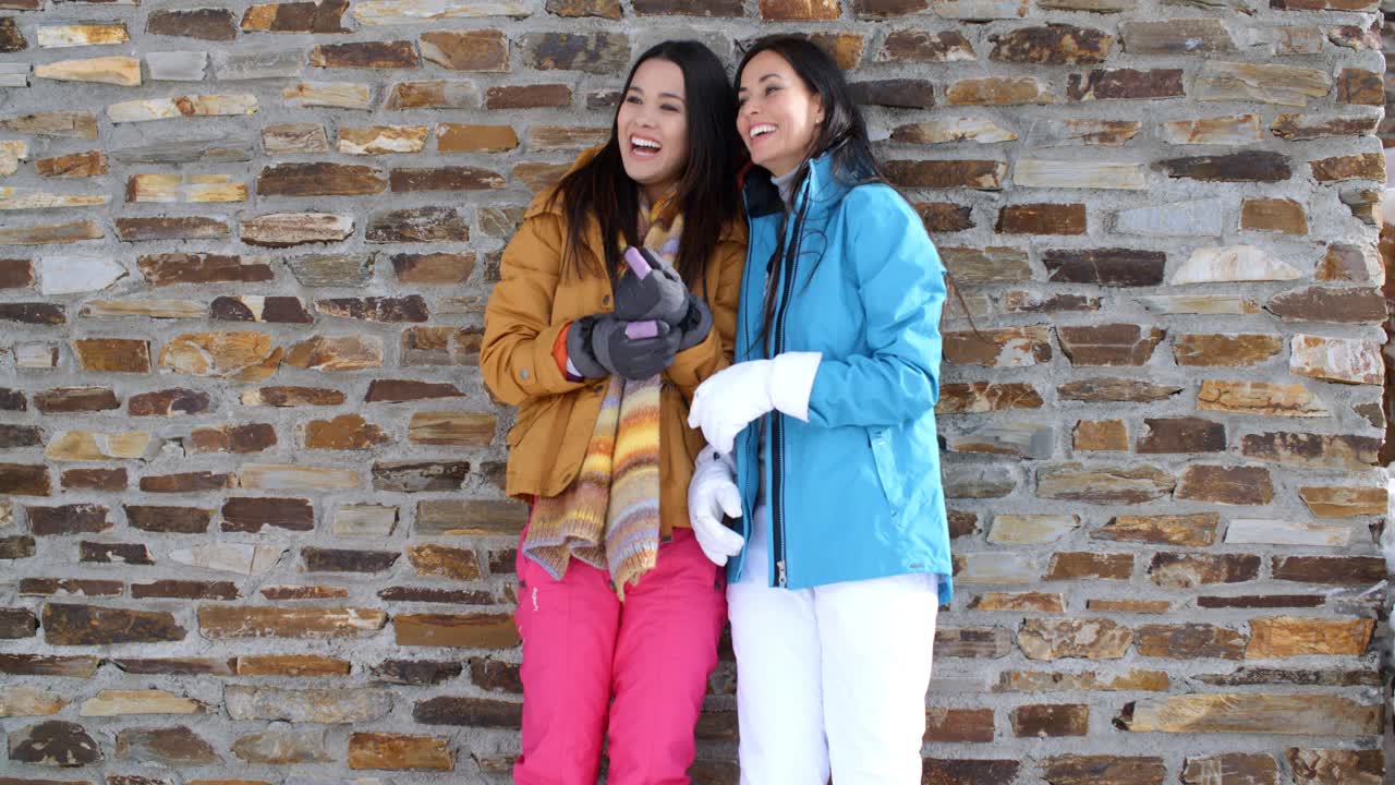 Cute twins in winter coats leaning on wall