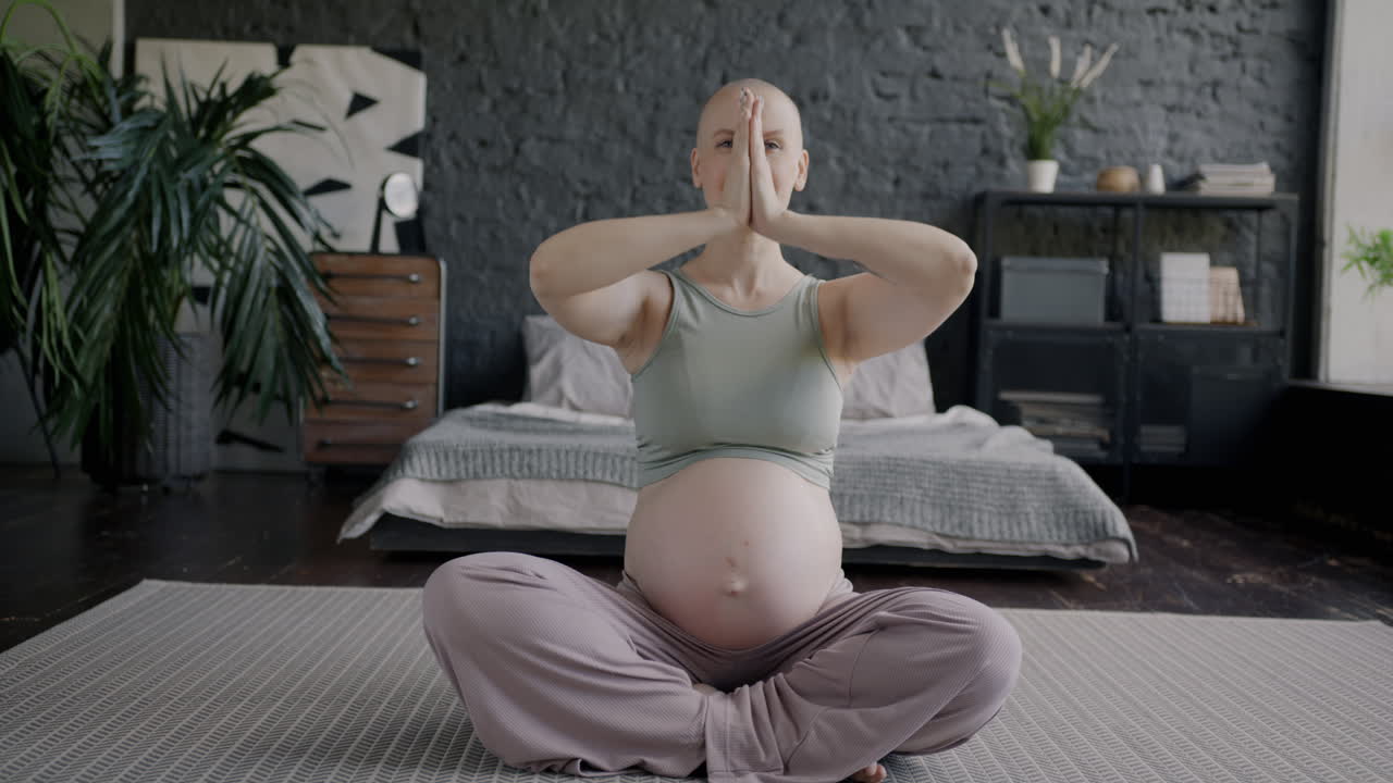 임신 한 여자 가 집 에서 요가 를 연습 하고 있다
