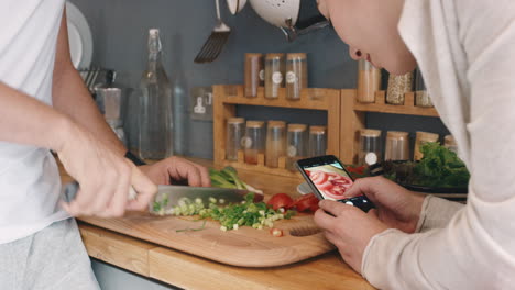 En-Casa,-En-La-Cocina,-Por-La-Mañana,-Una-Pareja-Feliz-Tomando-Fotos-Usando-Un-Teléfono-Inteligente-Para-Cortar-Una-Ensalada-Saludable-Para-El-Estilo-De-Vida-De-Las-Redes-Sociales.