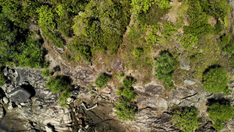 Top-view-of-a-small-island-with-rocks,-boats-and-a-beach