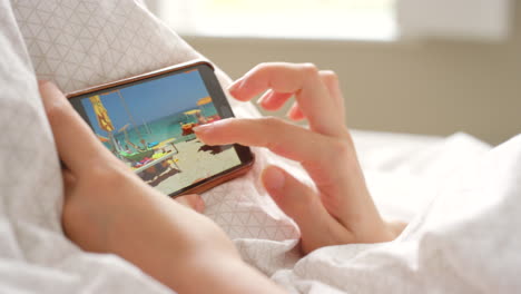 mujer en la cama mirando fotos en su teléfono