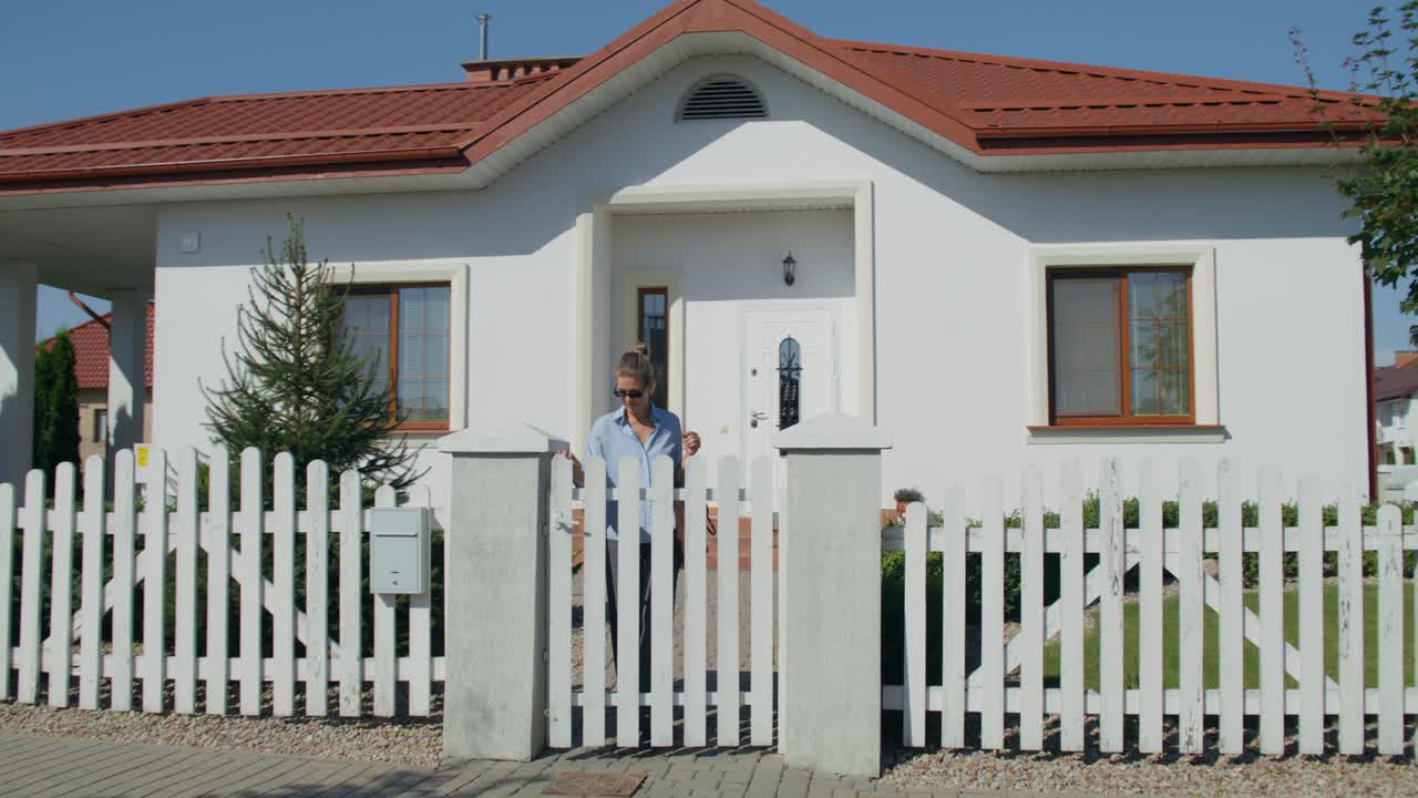 Kvinde foran et hus i forstaden