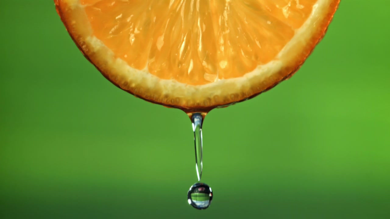Primo piano al rallentatore di succo che gocciola da una fetta d'arancia