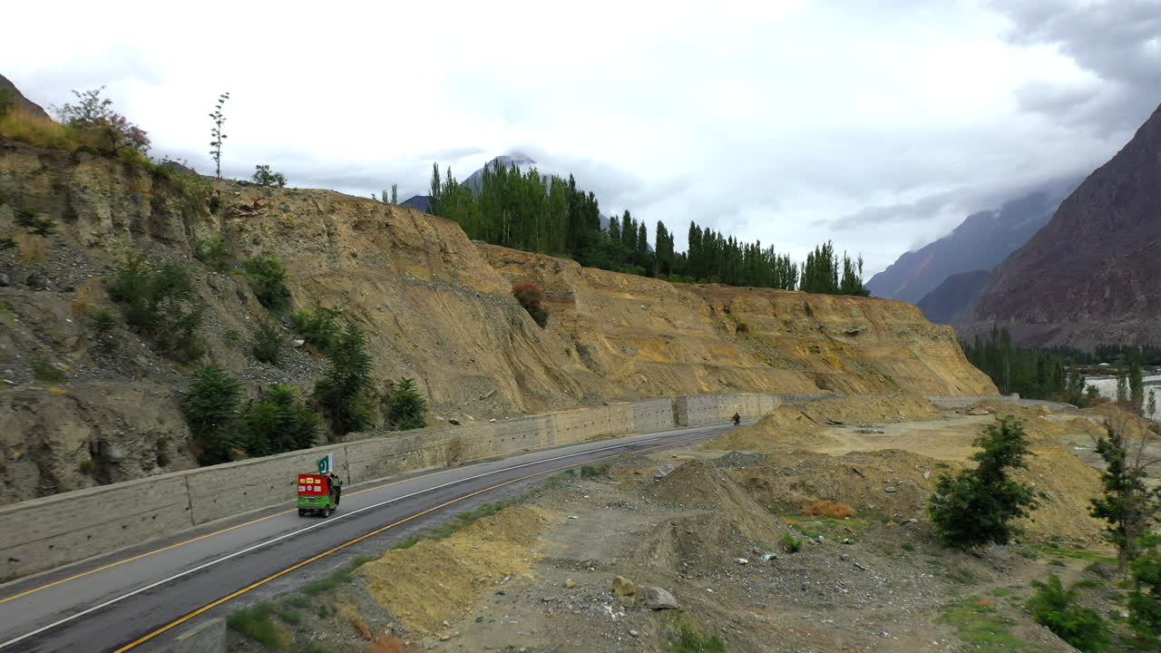 파키스탄 카라코람 고속도로의 자갈길에 있는 툭툭의 시네마틱 드론 샷, 거리에 있는 파수 콘과 함께 공중 샷을 쫓는