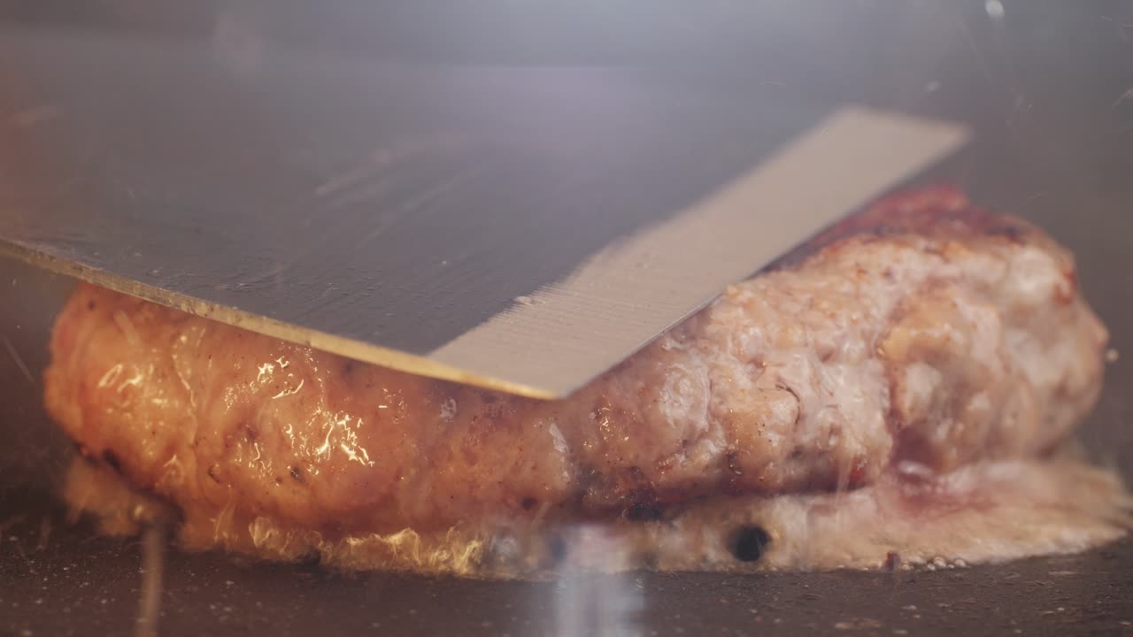 Cooking American fat smash burger on grill close-up. Beef or pork cutlet smashing by burger press. The chef in kitchen of the restaurant making cutlets for burgers - smash burger beefsteak. Fast and street food concept. High quality 4k footage