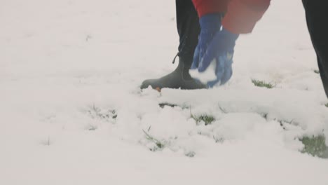 gay woman in blue winter gloves making snow balls, having fun during winter season