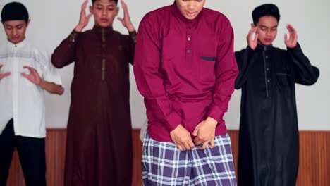 group of muslim young friends kneeling doing ruku and prostration pose praying salah together at the mosque