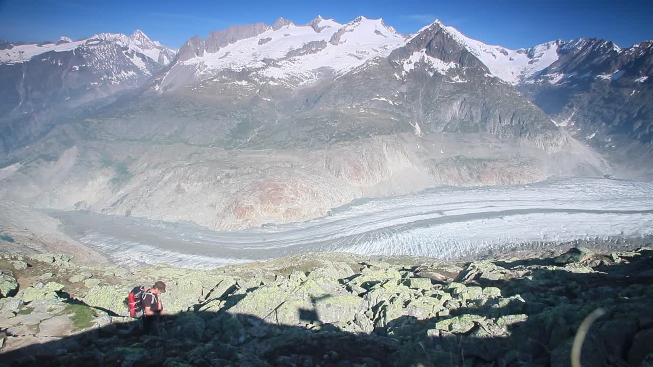 Hiker hiking above the Aletsch glacier in the Swiss Alps, view across the glacier
