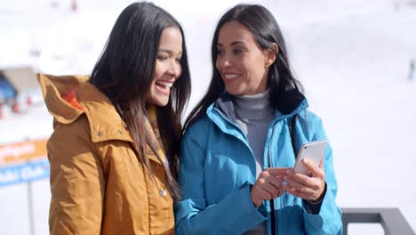 Two-smiling-young-women-checking-a-phone