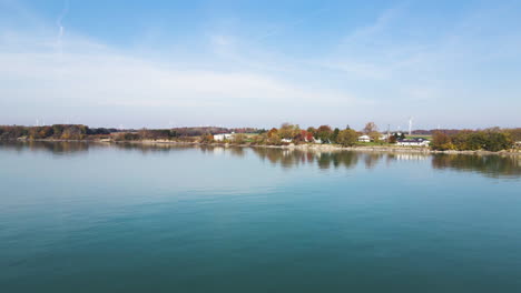 Peaceful-lake-side-view-under-wispy-grey-clouds-with-trees-reflecting-on-coast