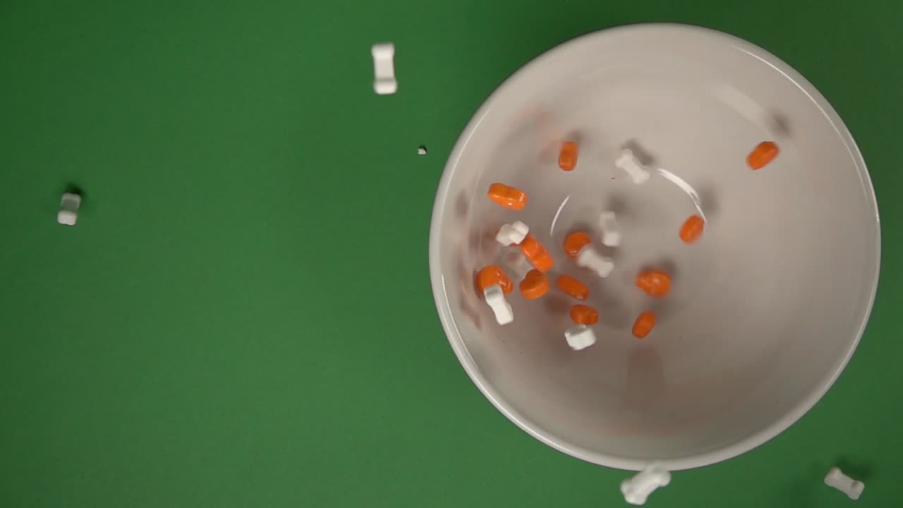 vista cenital de calaveras naranjas y dulces en forma de huesos cayendo sobre un plato