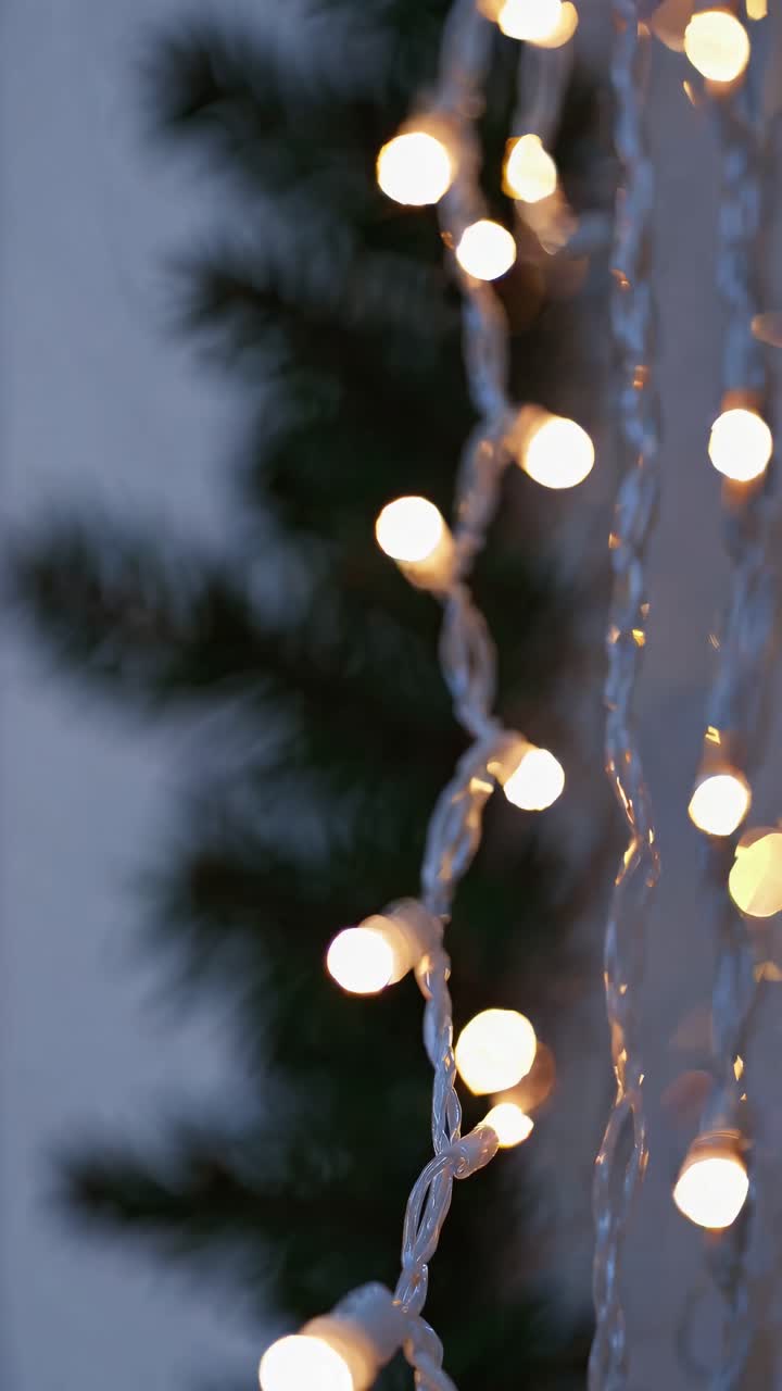 Blurred close-up of warm fairy lights against a dark background, shot from a side angle