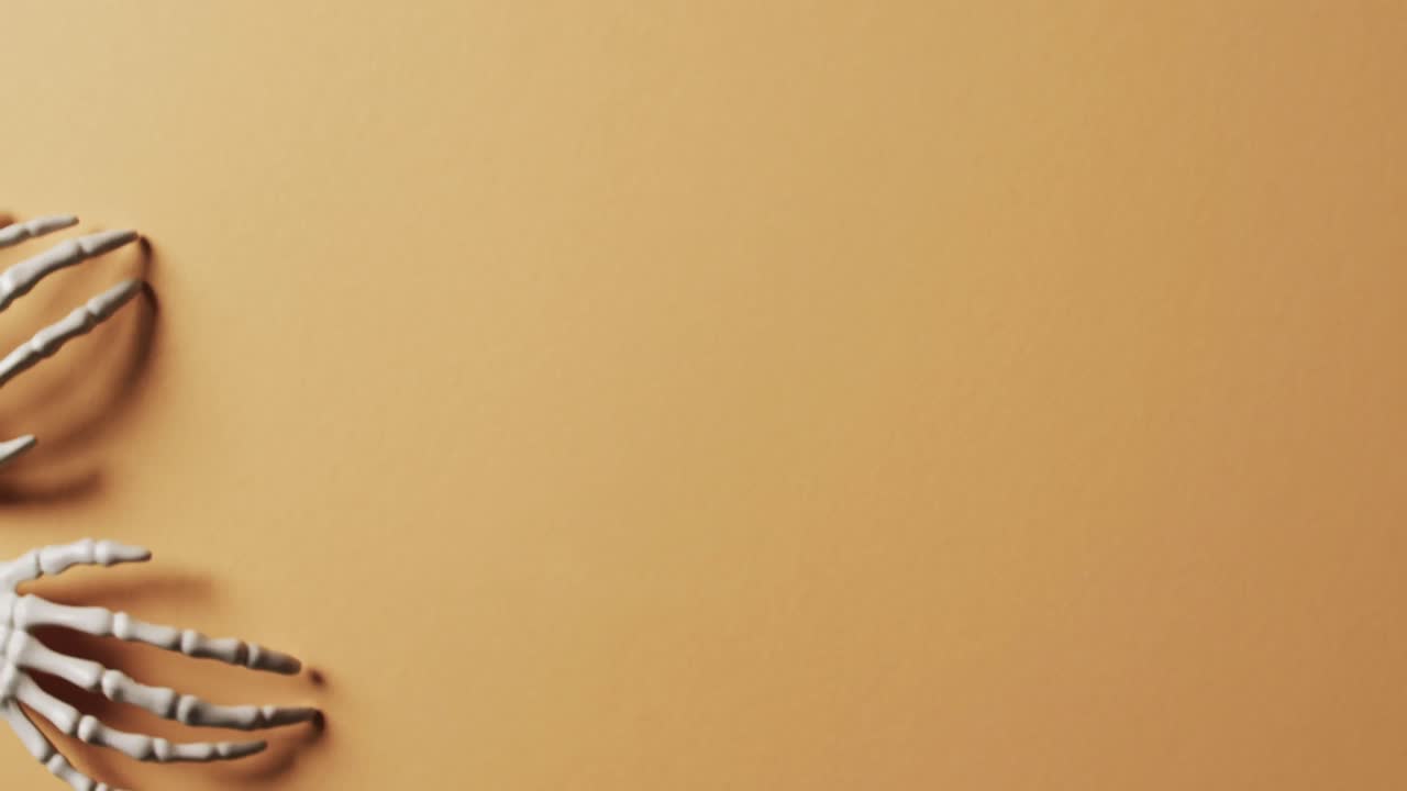 video de las manos del esqueleto de halloween con espacio de copia en fondo naranja