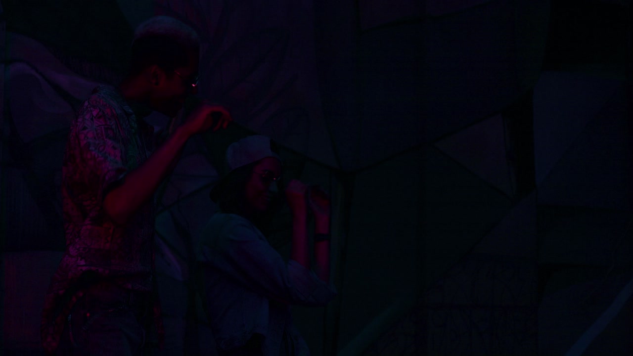 Stylish multiethnic hipster couple dancing in a party with neon lights at night