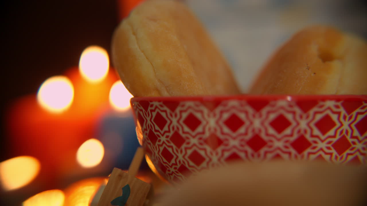 Hanukkah Donuts in a Red Bowl with Festive Lights and Dreidel