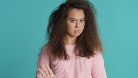 caucasian curly haired woman waving no in front of the camera.