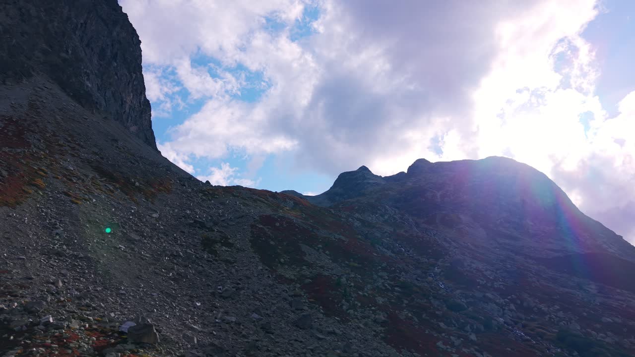 Raggi di sole che filtrano tra le nuvole su una cima montuosa aspra nelle Alpi Svizzere al Passo del Giulia.