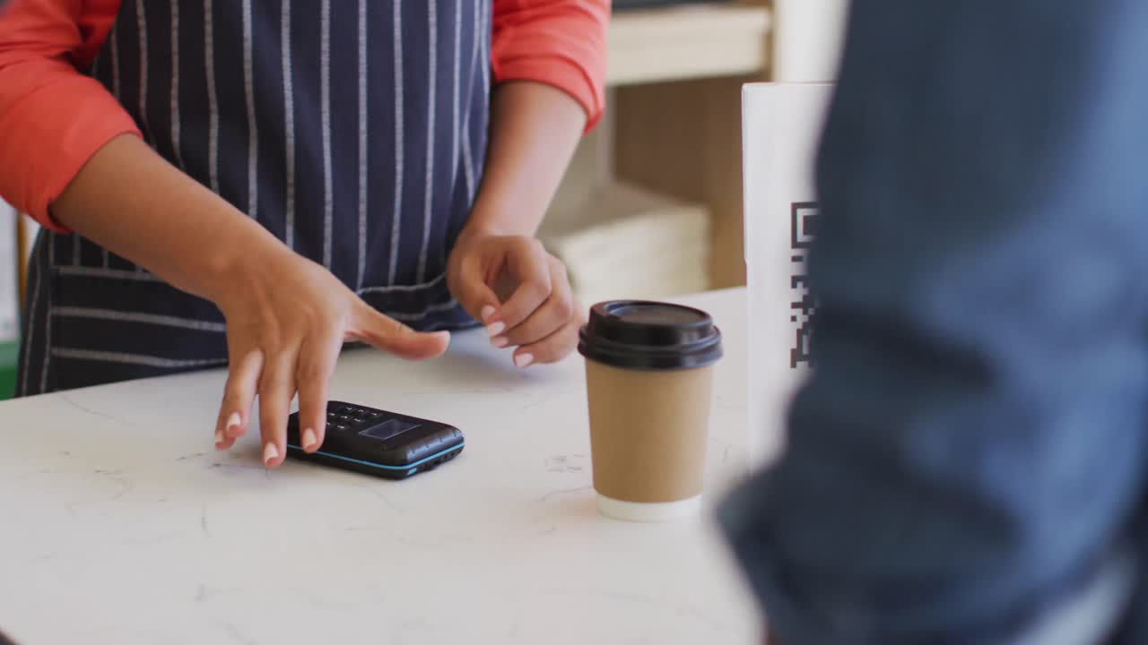 Video of hands of biracial waitress with payment terminal