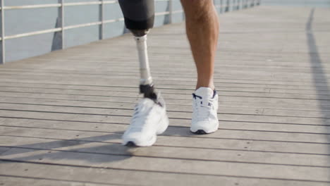 close up of an unrecognizable sportsman with artificial leg running along embankment in the morning 1