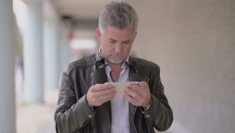 focused mature man using mobile phone