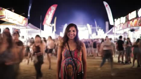 amid a bustling festival atmosphere, a smiling woman stands out against a backdrop of colorful tents and excited crowds. the night is alive with music and energy.