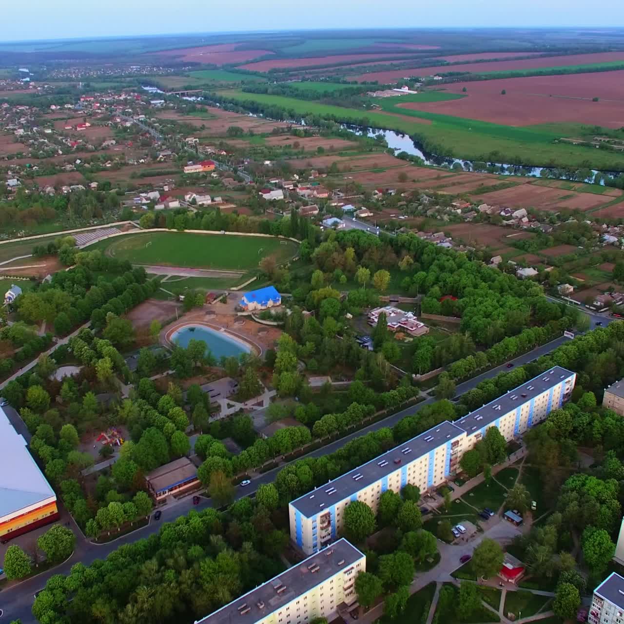 Large green city with multi-storied buildings and little private houses. Green parks and pond in the middle