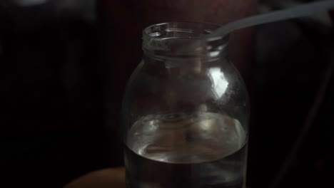 Vodka-destillation-drops-of-spirits-dripping-drop-by-drop-into-a-glass-jar