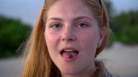 a white natural ginger girl with freckles releases a black bug out of her mouth in slow motion