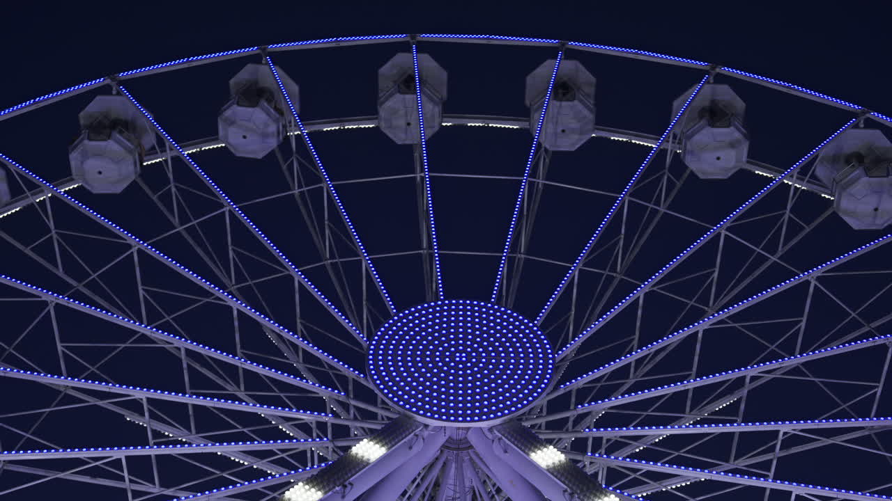 View of white, illuminated ferris wheel rotating in Antibes, France in the evening