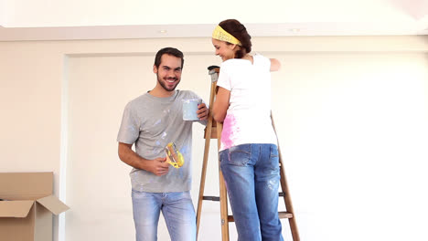 una pareja atractiva pintando su sala de estar.