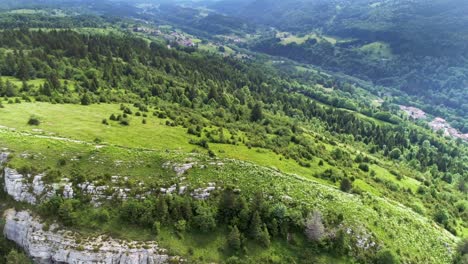 Drone-tracking-of-active-enduro-athlete-bicycling-down-the-green-mountains-in-France-during-summertime