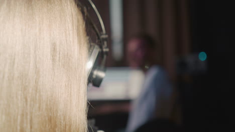 girl with blonde hair in audio studio closeup. skilled child sings song together with vocal teacher. professional vocal lessons in recording studio