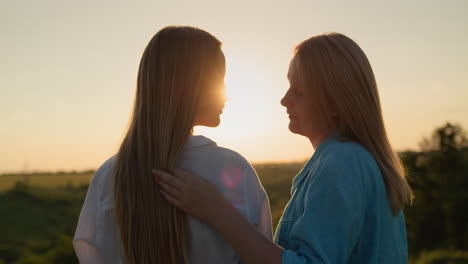 Mamá-Se-Comunica-Suavemente-Con-Su-Hija-Adolescente,-Parada-En-Un-Lugar-Pintoresco-Al-Atardecer.