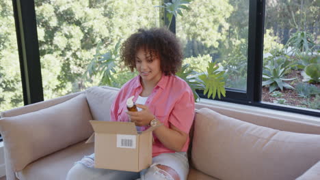 opening package, woman sitting on couch and smiling with excitement