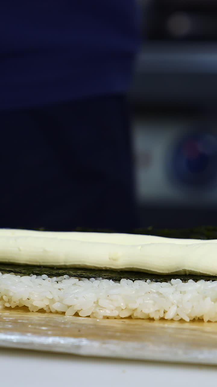 Chef puts cream cheese on sushi. The process of sushi cooking, preparing. Japanese cuisine concept. Process of complex dish. Vertical video