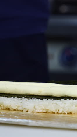 chef puts cream cheese on sushi. the process of sushi cooking, preparing. japanese cuisine concept. process of complex dish. vertical video