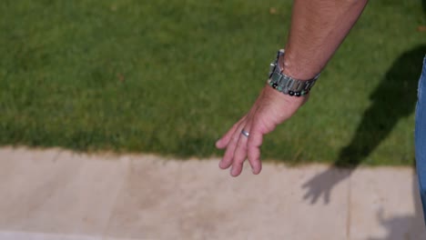 primer plano en la mano de un hombre caminando junto a una piscina de piedra en bali
