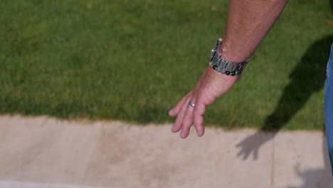 close-up on the hand of a man walking next to a stone swimming pool in bali