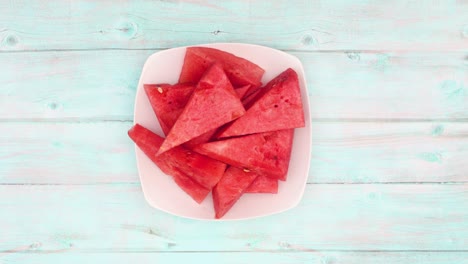 hand taking slices of watermelon from the white dish. stop motion