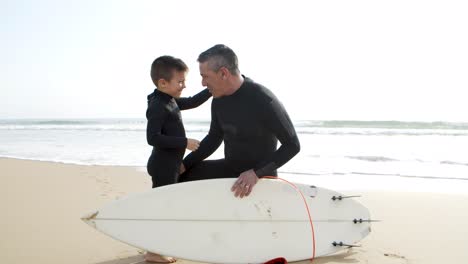 Padre-E-Hijo-En-Trajes-De-Neopreno-Hablando-En-La-Playa